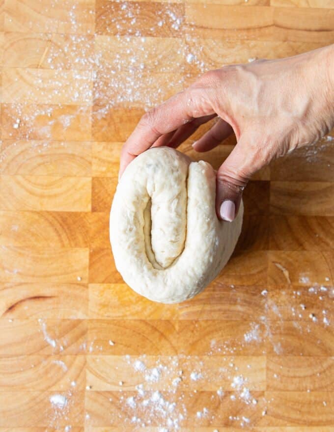 A hand holding the folded dough close up showing the three folds clearly 
