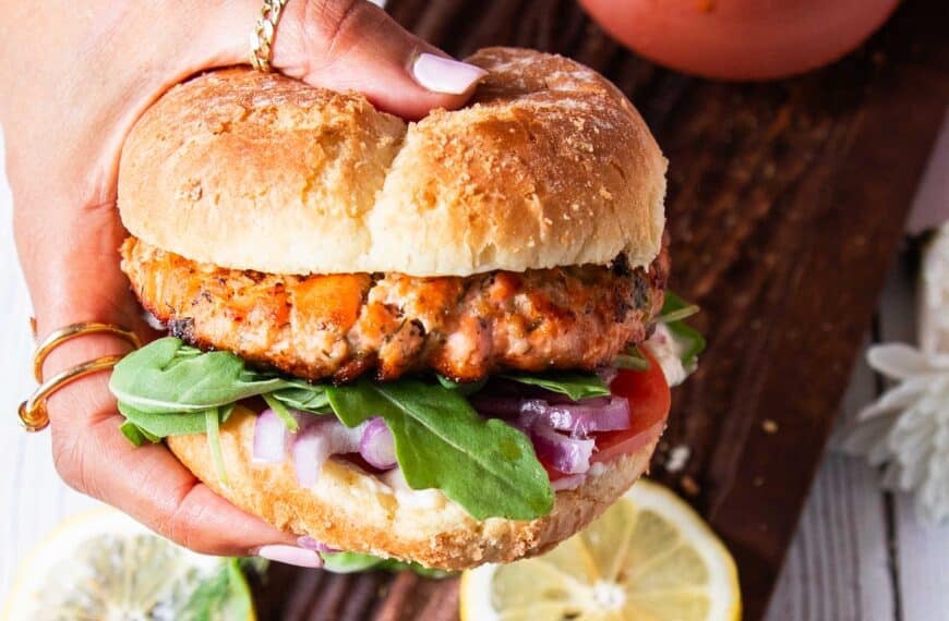 A hand holding salmon burgers assembled and ready