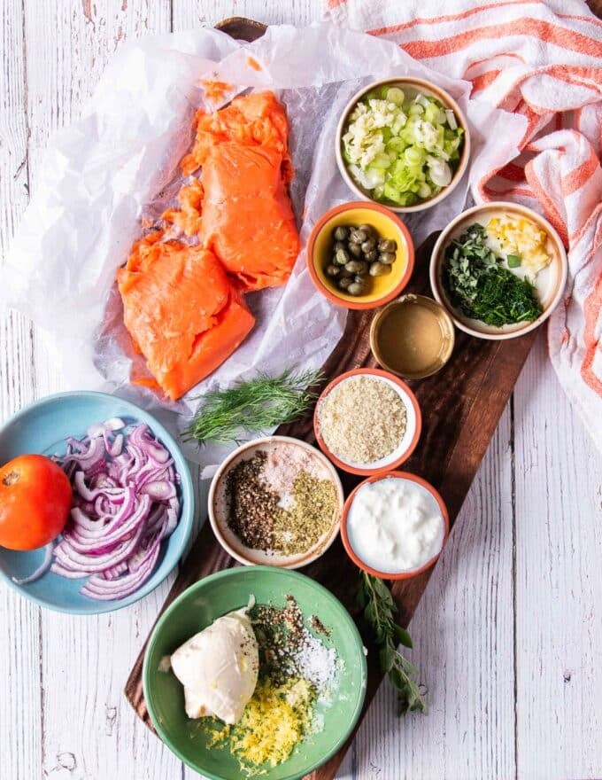 salmon burger ingredients on a board and salmon burger sauce ingredients, all in small bowls and measured 