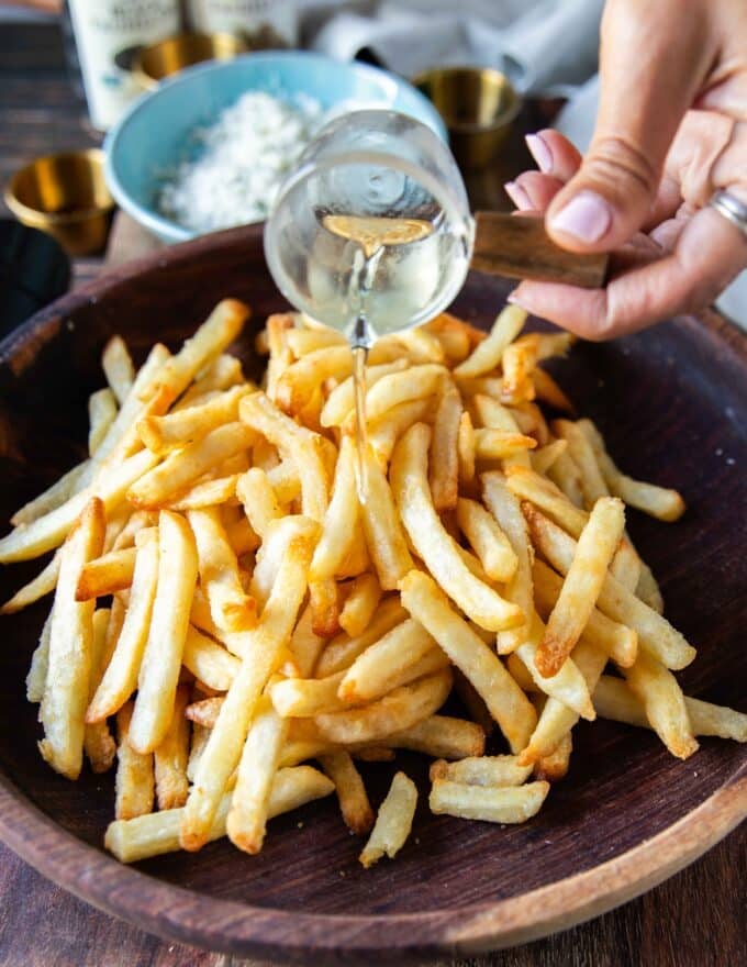 Pouring truffle oil for truffle flavor over the cooked potatoes fries 