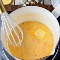 Whisking the butter into the beurre blanc one a time to make beurre blanc sauce