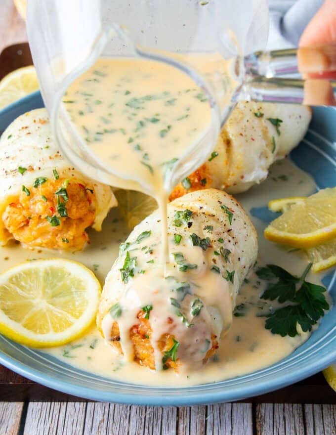 beurre blanc sauce pored over scallops and cooked fish in a plate
