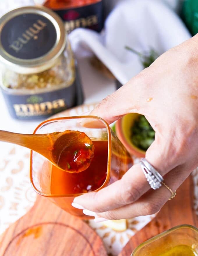 A hand holding a jar of harissa vinaigrette close up