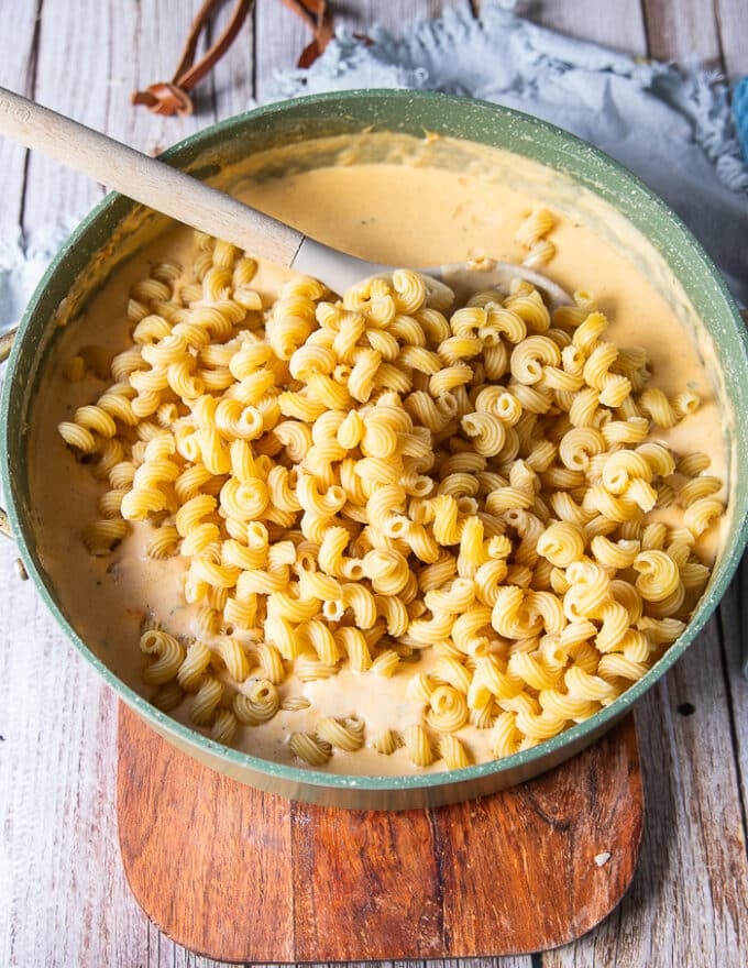 cooked pasta is added to the cheese sauce 