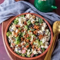 creamy broccoli and cauliflower salad on a plate with crunchy candied walnuts ontop