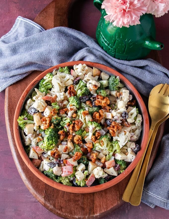 creamy broccoli and cauliflower salad on a plate with crunchy candied walnuts ontop
