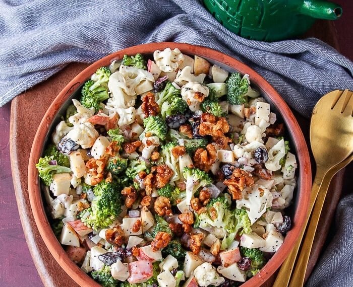 creamy broccoli and cauliflower salad on a plate with crunchy candied walnuts ontop
