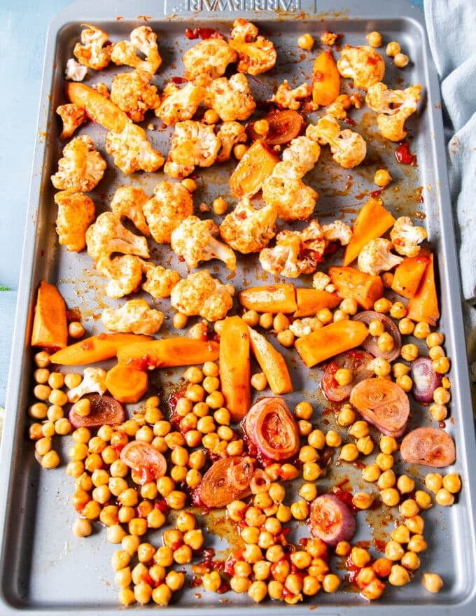 Seasoned veggies on a baking sheet ready to roast to make cauliflower salad 