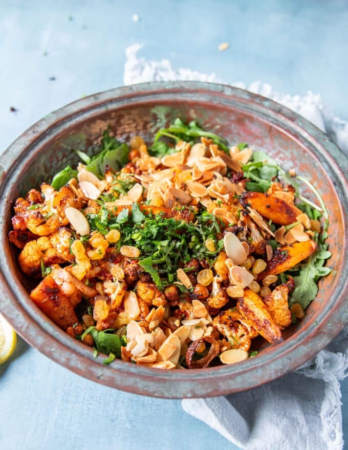 the tender roast cauliflower and crips chickpeas are added over the arugula, along with toasted almonds, herbs and raisins to make cauliflower salad 