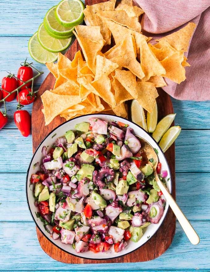 octopus ceviche mixed and marinated with onions, chilies, cilantro and lime with tortilla chips around it 