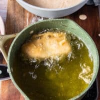 Perfectly coated fish frying in a pot of hot oil