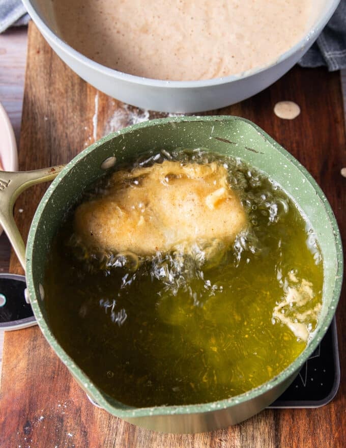 Perfectly coated fish frying in a pot of hot oil