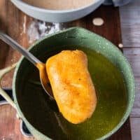 Perfectly golden and crisp fried fish in a slotted spoon lifted from the oil