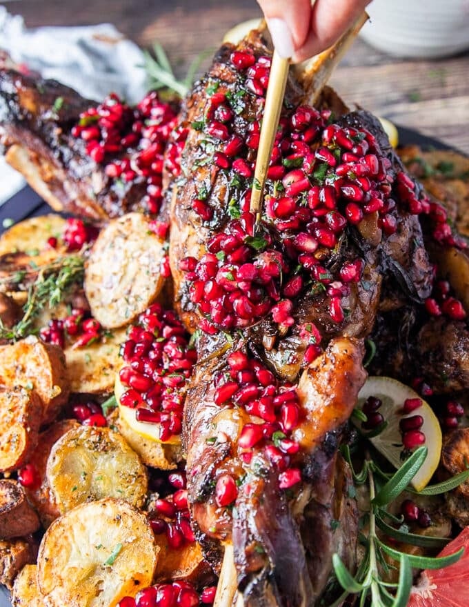 A spoon adding the pomegranates over the lamb