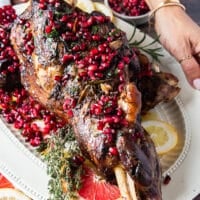 A hand holding a large plate of roast lamb shoulder recipe perfect and succulent