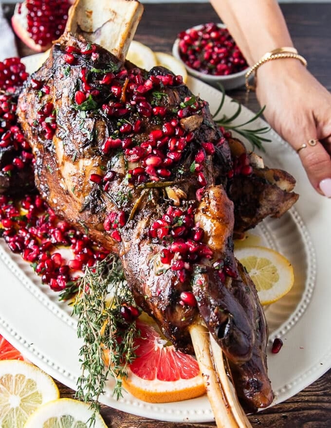 A hand holding a large plate of roast lamb shoulder recipe perfect and succulent 