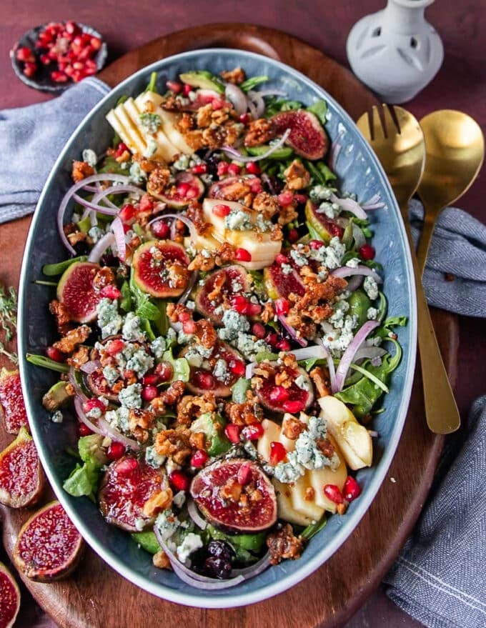 Finished plate of fig salad with blue cheese, candied walnuts, pomegranates , avocado, arugula and apples