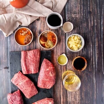 Ingredients to make flank steak tacos including the flank steak, the marinade ingredients in small bowls, the remaining taco toppings in small bowls separate on a board