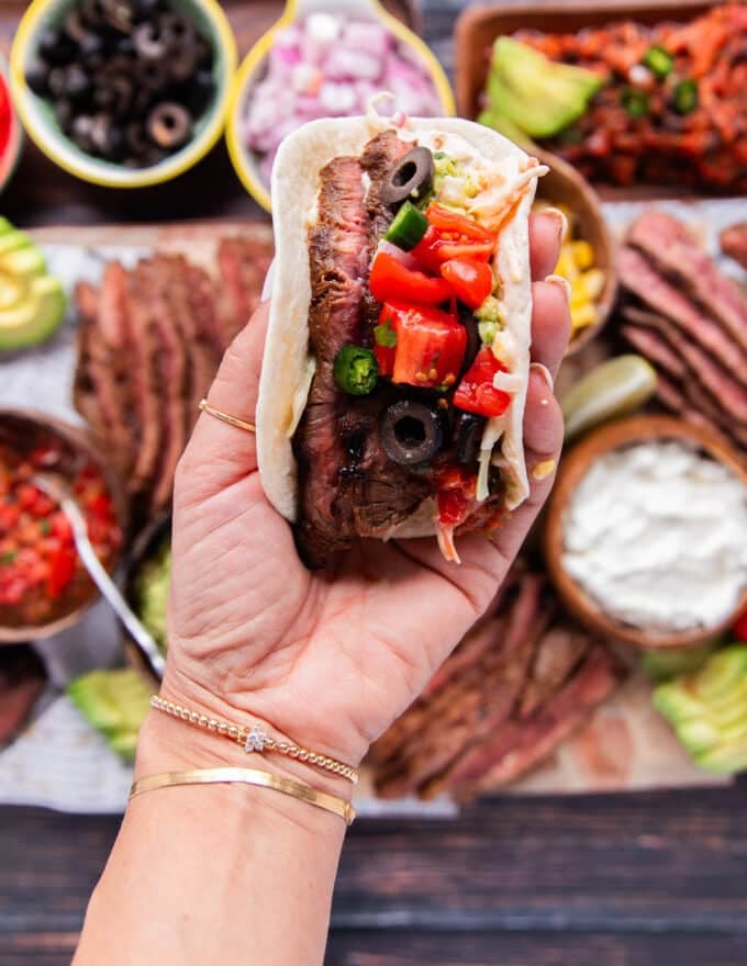 finished flank steak taco close up with sauce, added, some fresh onions, cilantro, tomatoes, jalapenos and more