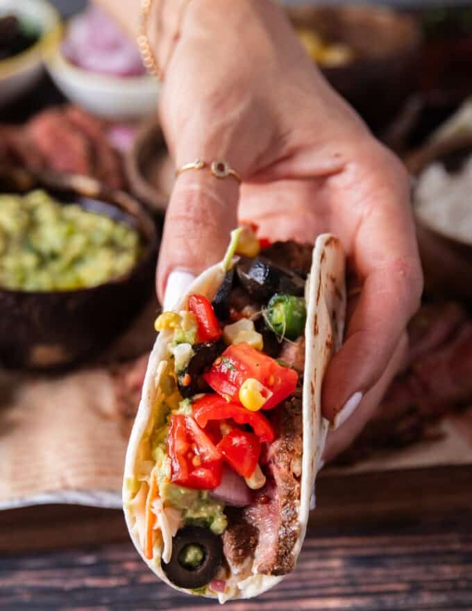 A hand holding a flank steak taco close up