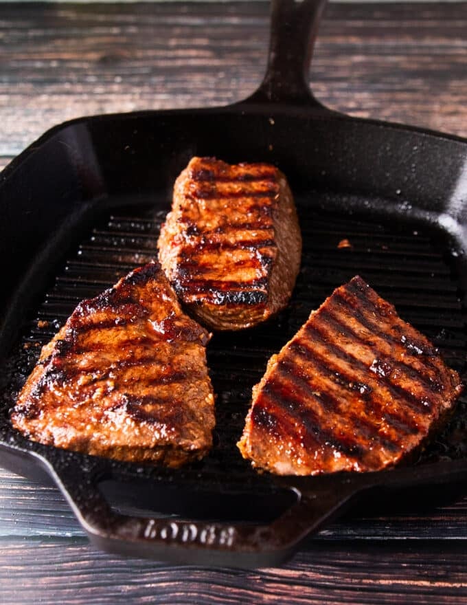 flank steak is cooked in a super hot skillet or outdoor grill showing grill marks