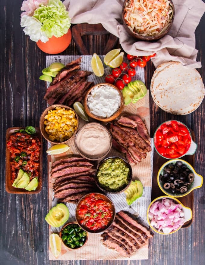 The taco board is assembled with the sliced flank steak, all the taco toppings, tortillas and more!