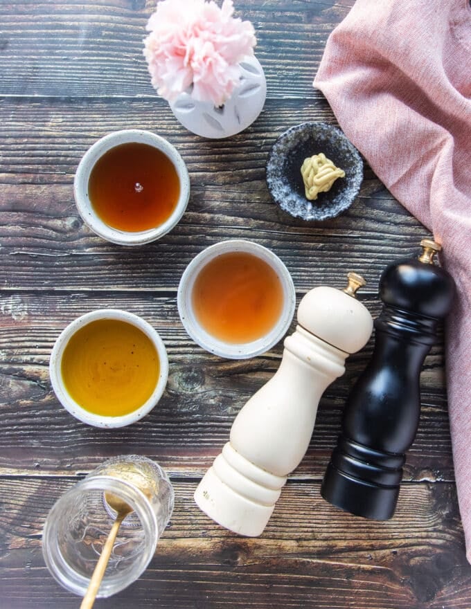 Ingredients on a board to make maple vinaigrette including maple syrup, olive oil, vinegar, mustard