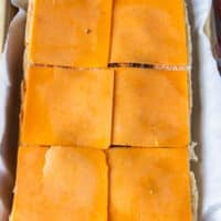 A layer of sauce and cheese are added at the bottom of the slider bread