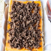 burger meat is added over the cheese