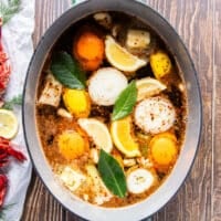 A large pot of water with all the aromatics added to make crawfish boil base