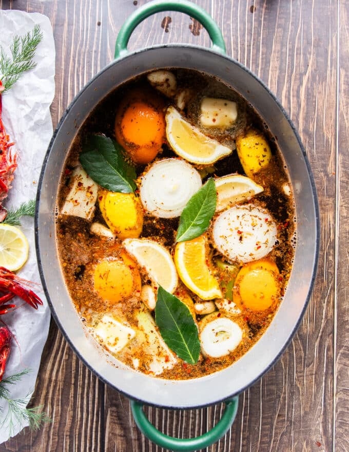 A large pot of water with all the aromatics added to make crawfish boil base