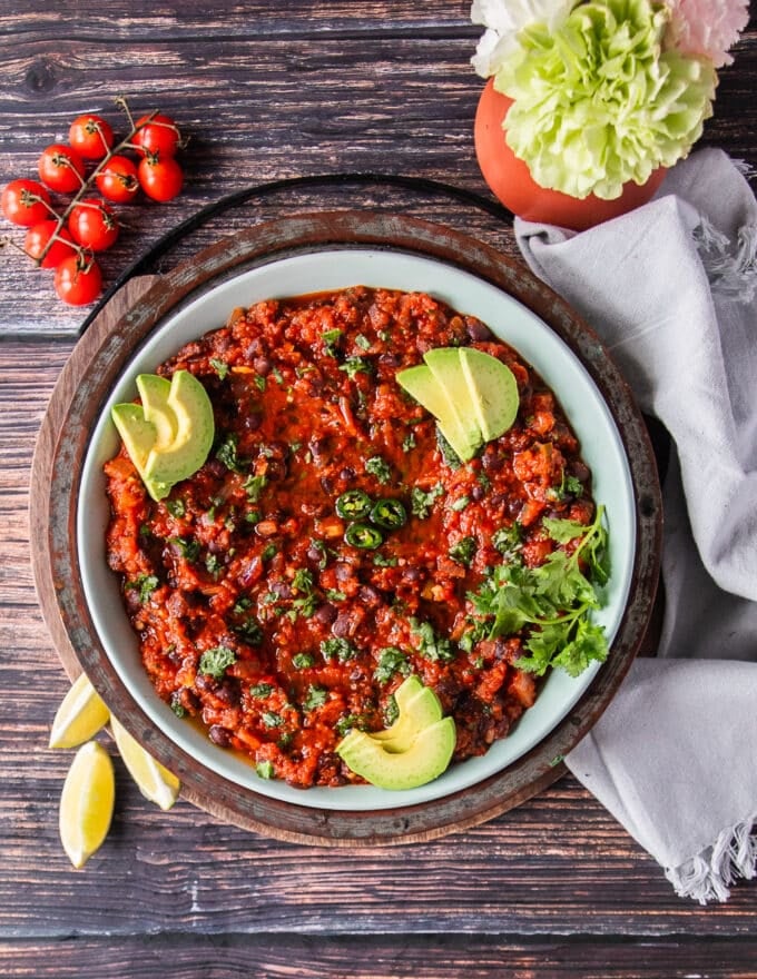 finished plate of mexican blsck beans or Frijoles Negros surrounded by chips and lime wedges 