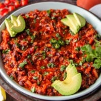 close up of Mexican black beans plate topped wtih avocado slices, cilantro and jalapeños