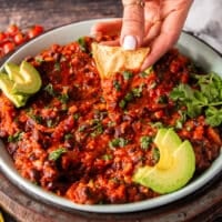 A hand scooping some mexican black beans with chips