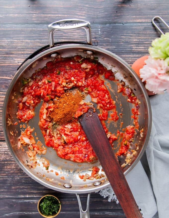 Tomatoes and seasoning are added to the sauce pan 