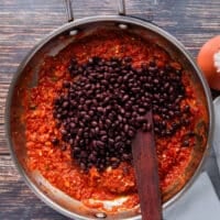 Black beans are added to the pan to continue cooking