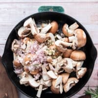 A heavy duty cast iron with oil, butter, mushrooms, shallots and garlic