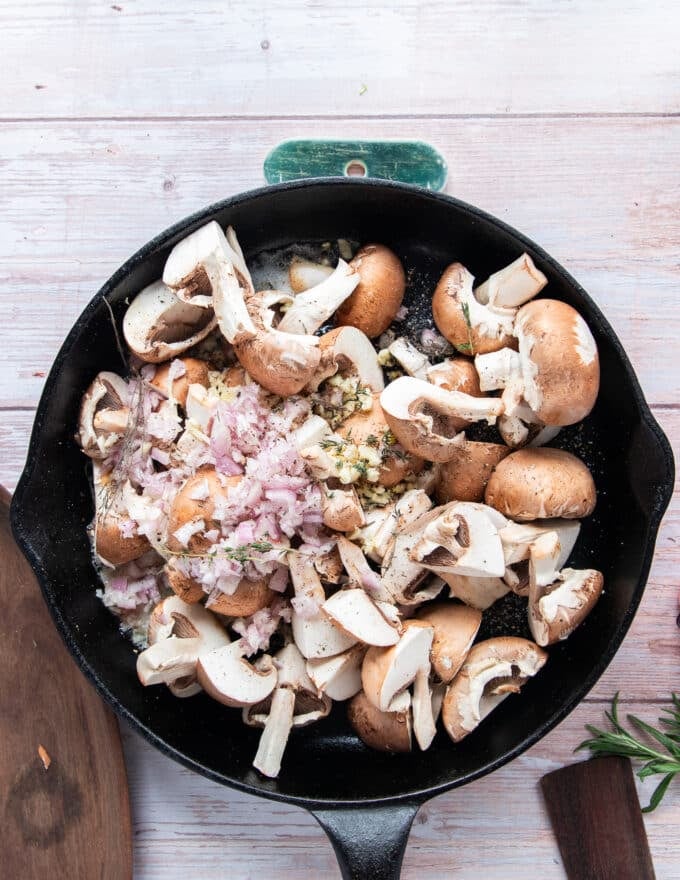 A heavy duty cast iron with oil, butter, mushrooms, shallots and garlic