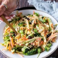 A hand using a fork to spoon in some crunchy broccoli slaw