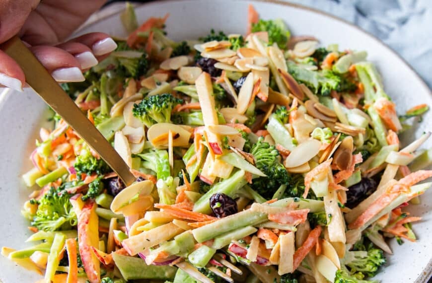 A hand using a fork to spoon in some crunchy broccoli slaw