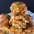 close up of a tower of 4 stacked chicken sliders with cheese oozing out and soft bread