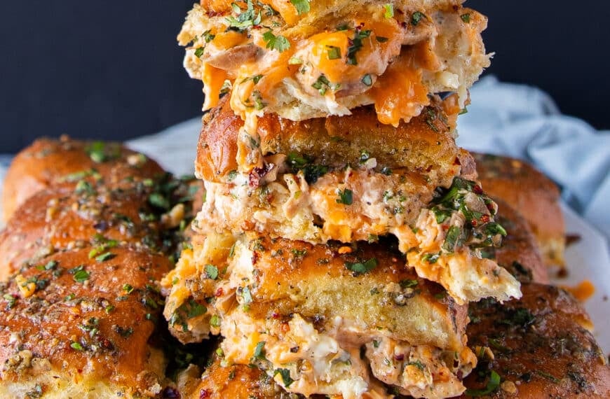 close up of a tower of 4 stacked chicken sliders with cheese oozing out and soft bread