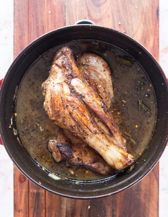 the lamb shanks and liquid are added to a slow cooker to slow cook 