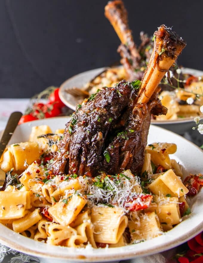 close up of slow cooked lamb shanks served over sun dried tomato pasta 