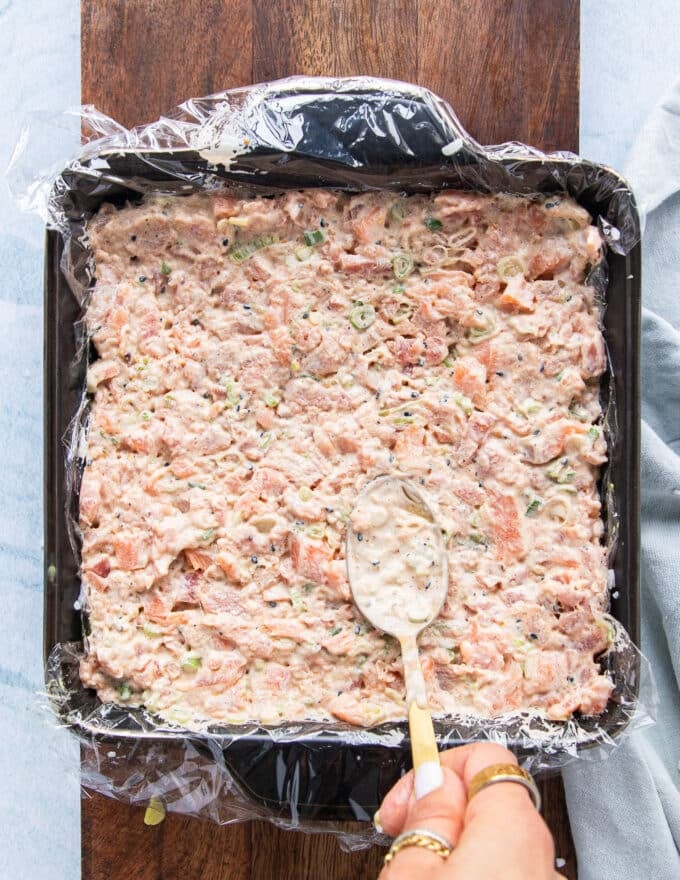 the fish mixture is now added over the avocado layer to make the filling for the sushi cake 