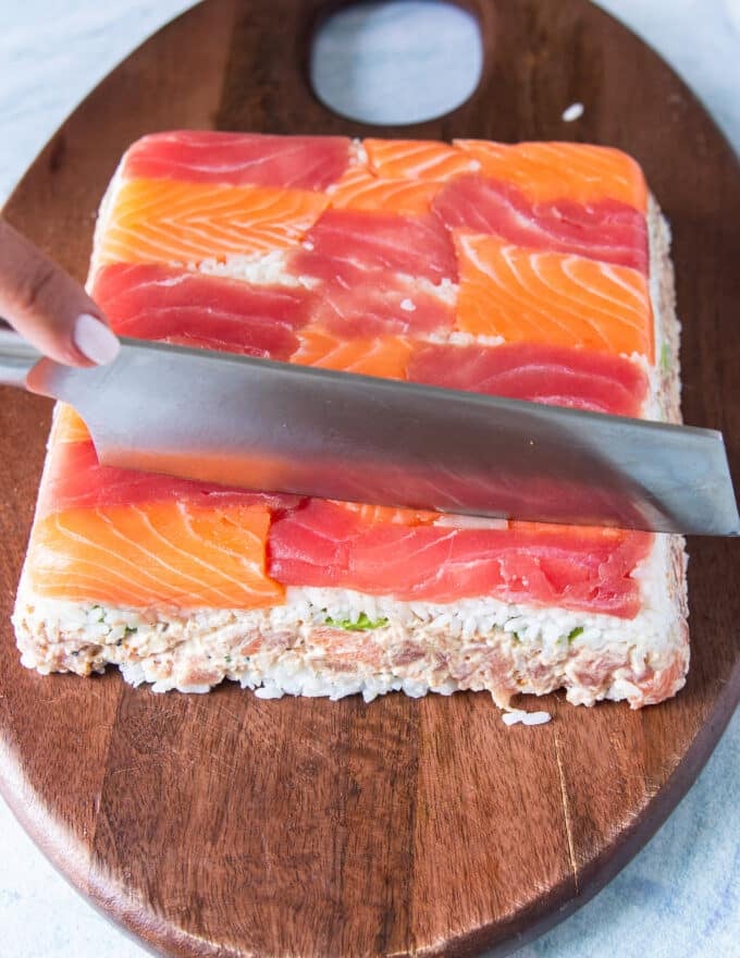 The sushi cake is inverted on to a board and then sliced or cut into small dice
