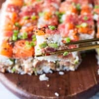 A chop stick holding a pice of the sushi cake close up showing the layers
