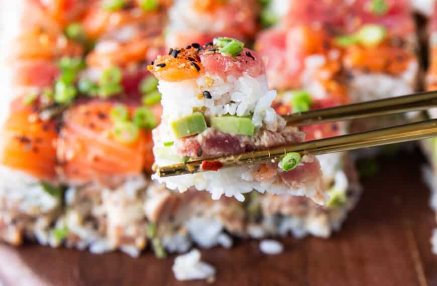 A chop stick holding a pice of the sushi cake close up showing the layers