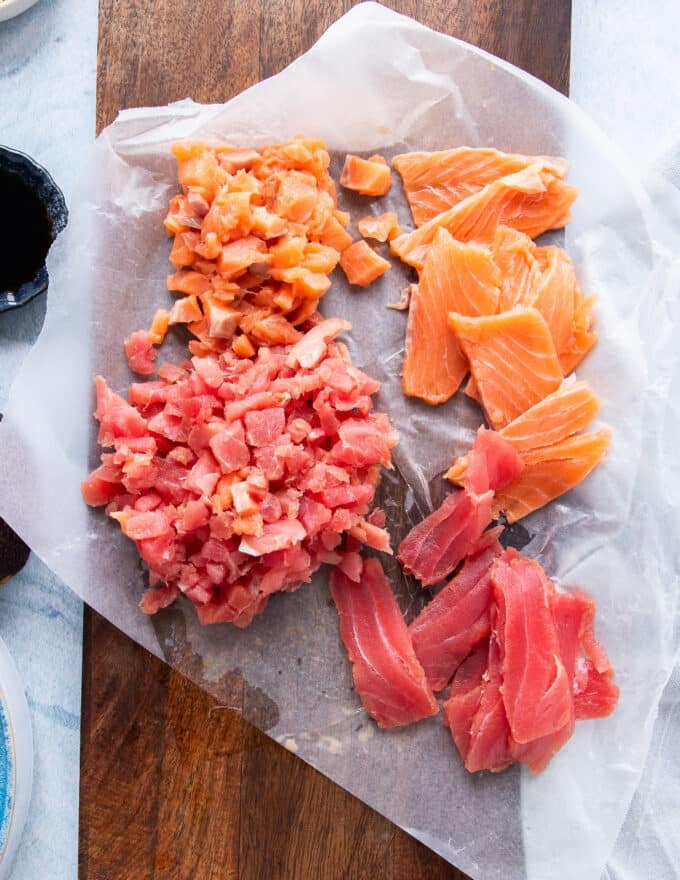 Sushi grade salmon and tuna on a white parchment paper, half of them diced for the filling and the other sliced for the topping 
