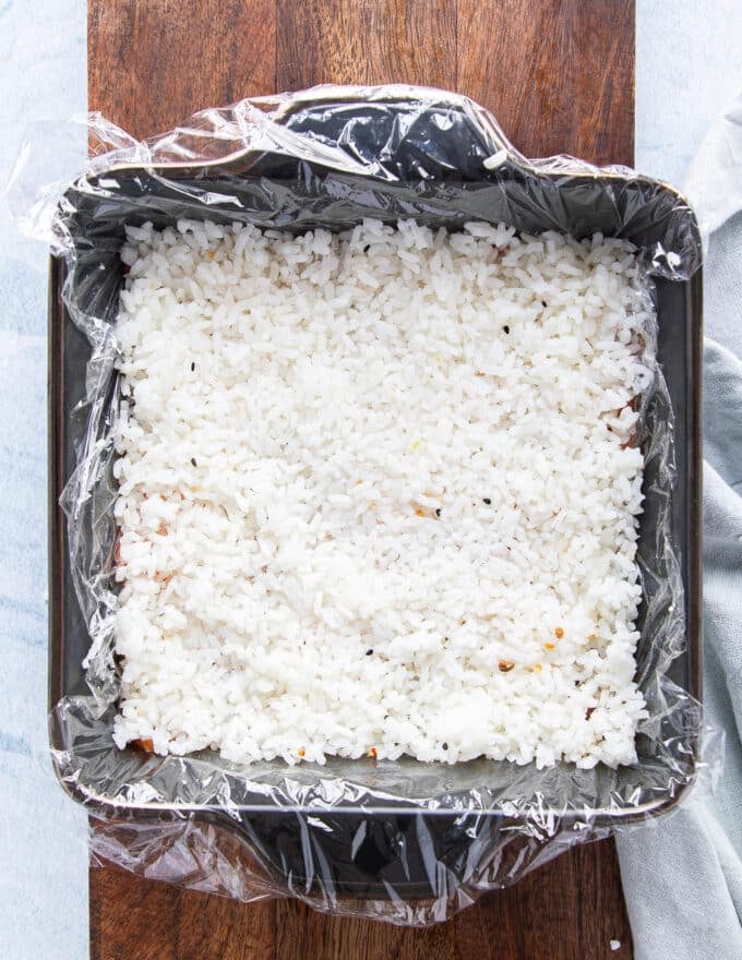 First layer of rice is added to the sushi cake and pressed firmly 